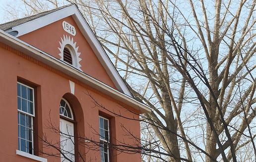 The exterior of the Grace Atelier building, an orange-bricked house with a tree in front.